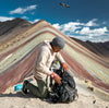 A man looking for something in his backpack in front of the Rainbow mountain