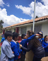 Gisella hugging some peruvian students with a beautiful blue sky in the background