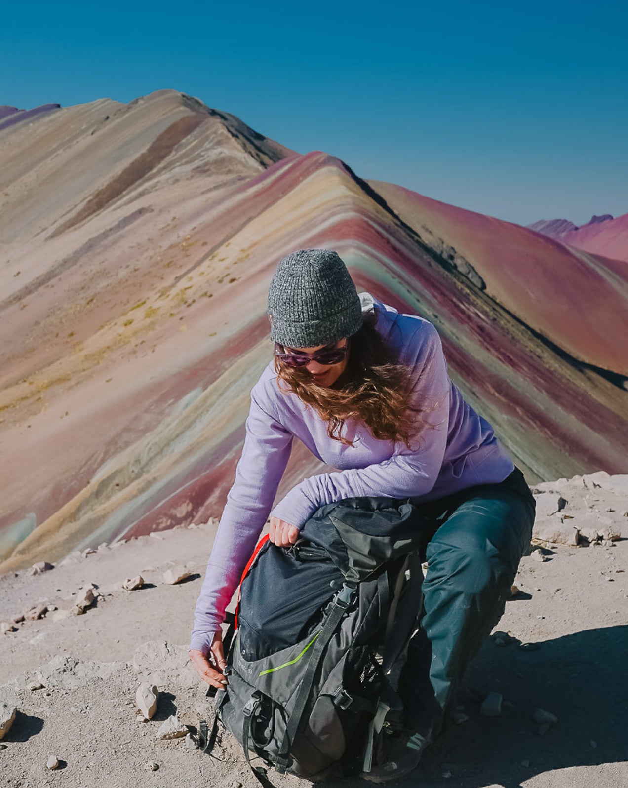 A woman wearing our lavender Breathe Women's Hoodie in front of the Rainbow Mountain in Peru