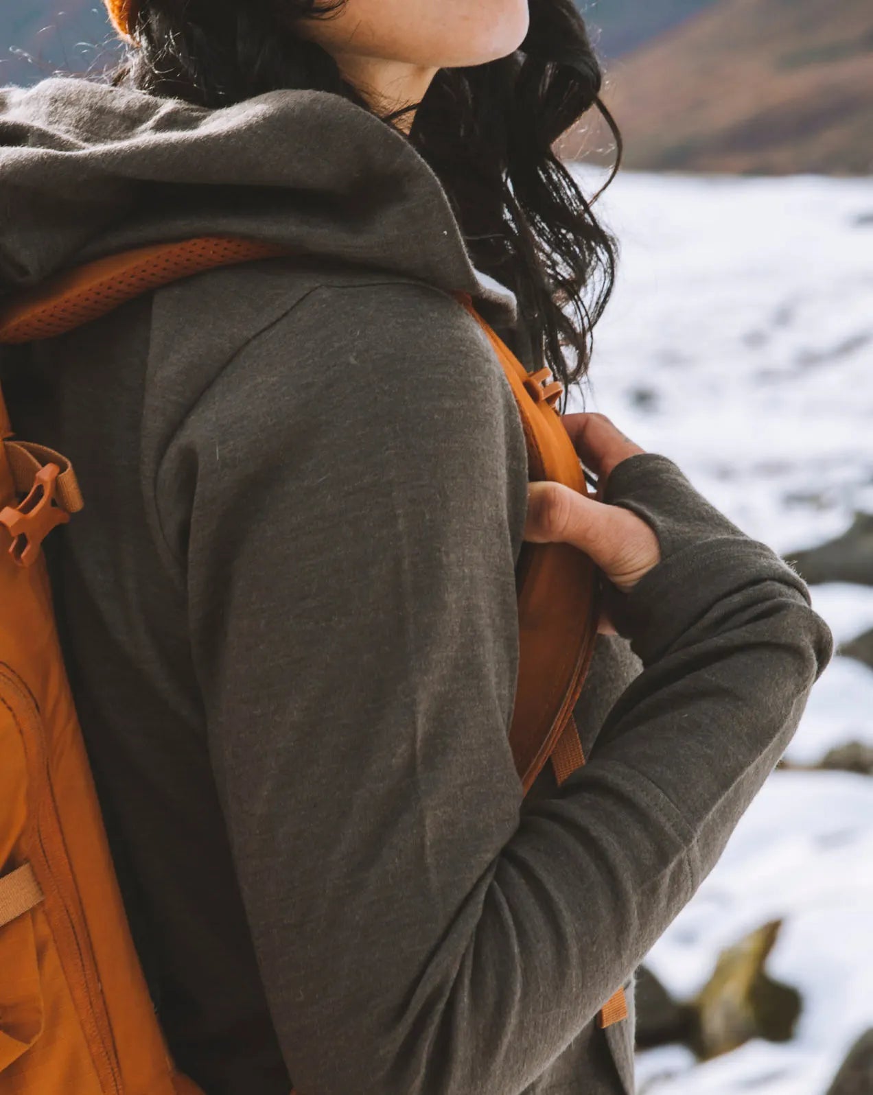 Woman wearing alpaca hoodie and orange backpack