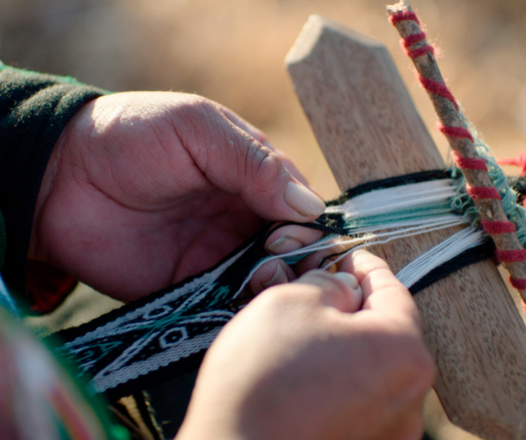 A woman's hands weaving a bracelet with an ancestral tool 