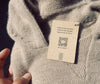 A light grey alpaca hoodie with a tag that says 
