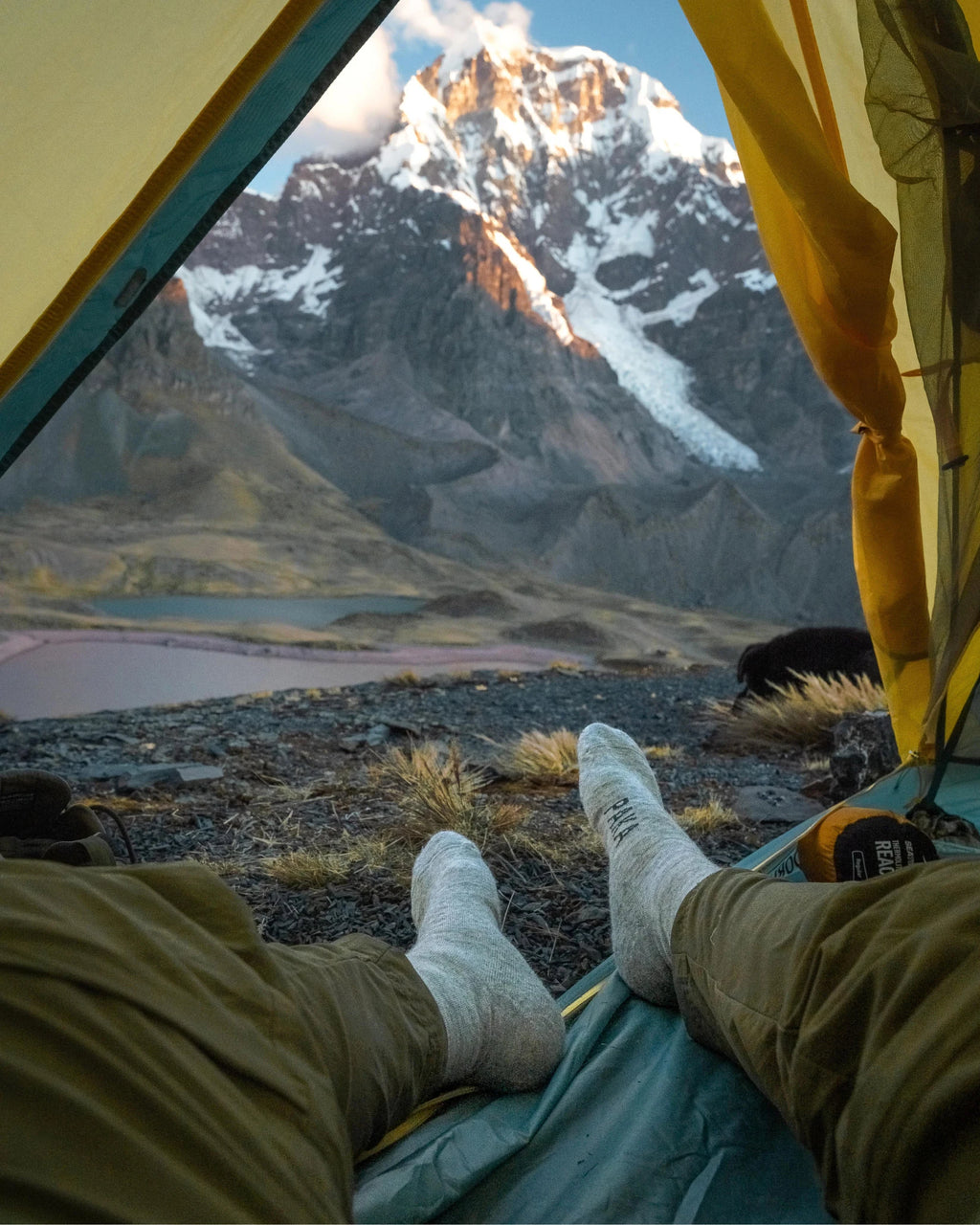 Men’s Alpaca Socks in Light Grey Worn on Feet in Tent with View of Snowy Mountain – PAKA Apparel