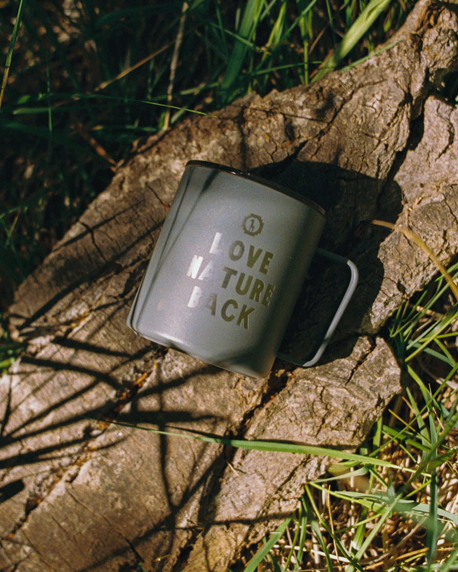 Mug with 'Love Nature Back' text on a stone surface with grass