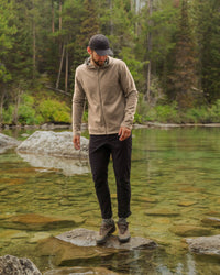 Man wearing timber Men’s Breathe full-zip hoodie, slim athletic fit, standing on rocks in a clear forest stream