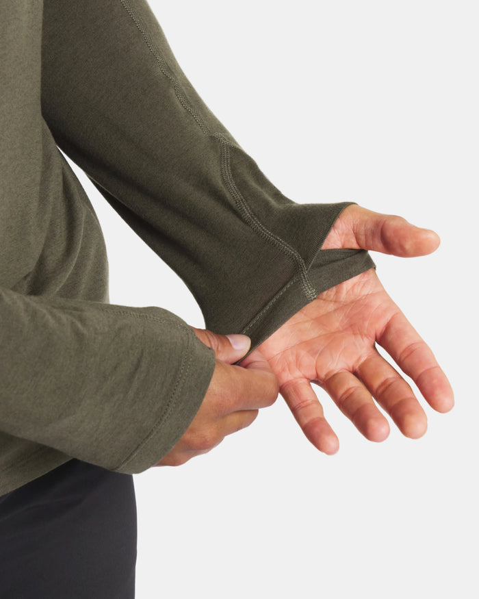 Person wearing a green long-sleeve shirt with a close-up of the sleeve and hand.