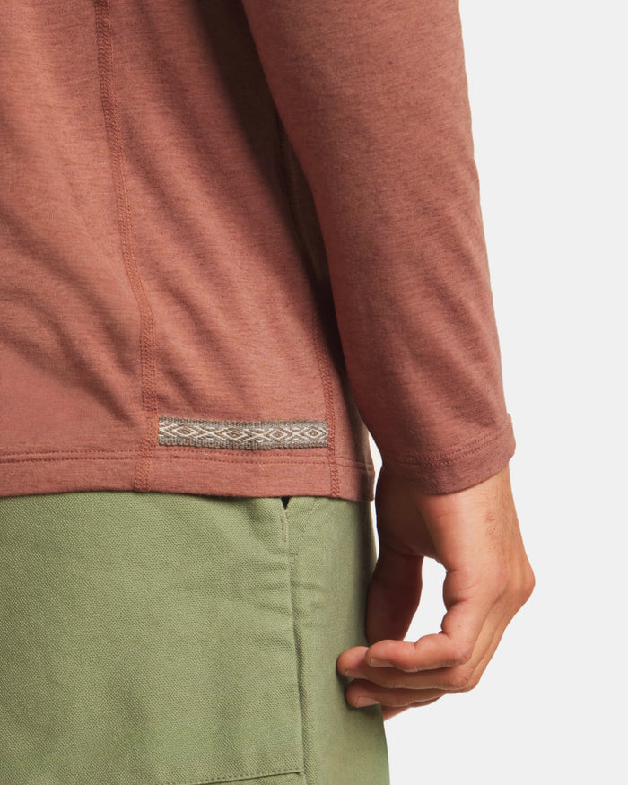Close-up of a person wearing a brown long-sleeve shirt with a green pocket on a white background
