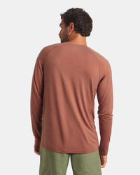 Man wearing a brown long-sleeve shirt and green pants on a white background