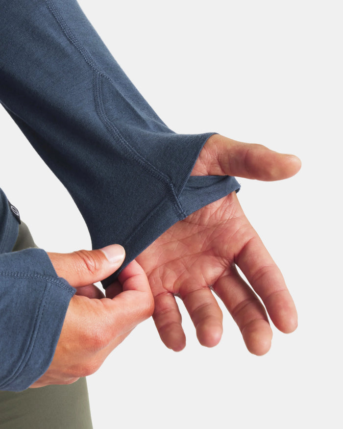 Person adjusting the sleeve of a blue jacket on a white background