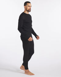 Man Looking Sideways in Black Alpaca Wool Thermal Baselayer Top and Bottom for Skiing and Winter – PAKA Apparel