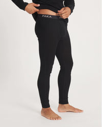 Side view of men’s alpaca thermal bottoms in black showing snug fit, seam detailing and PAKA waistband on light background