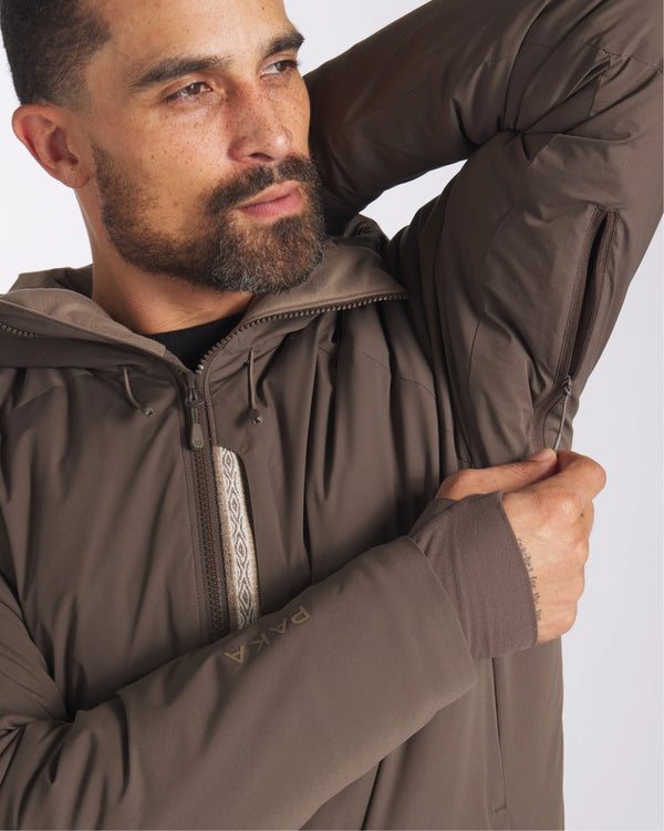 Male Model Zipping Arm Vents on Apu Wood / Brown Rainproof Parka Sustainable Winter Ski Jacket – PAKA Apparel