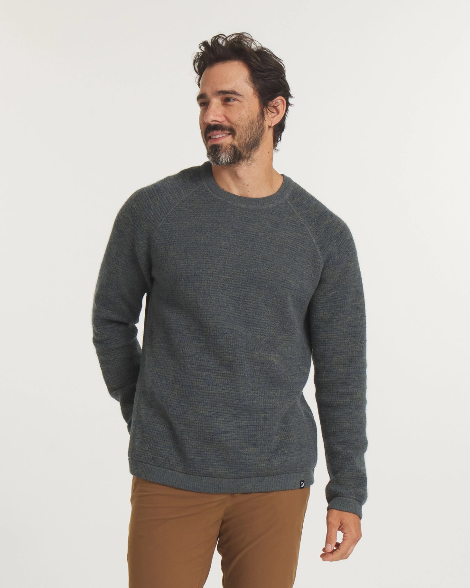 Man wearing a green sweater and brown pants on a white background