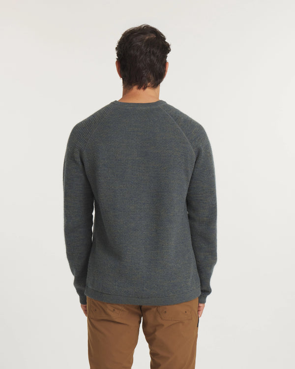 Person wearing a green sweater and brown pants on a white background