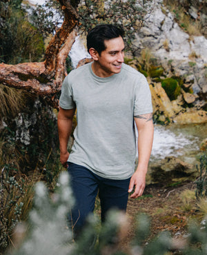 Man standing in a natural setting with trees and water in the background