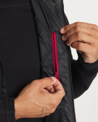 Close-up of Men’s Mayu Ultralight Vest interior showing magenta inner zip pocket and hands on a black base layer