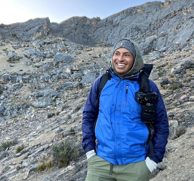 A man smiling wearing an alpaca beanie in the mountains 