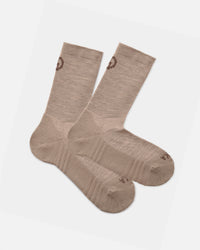 Flat lay of Trail Crew Socks in tan showing ribbed cuff, cushioned footbed, reinforced heel and PAKA logo on gray background