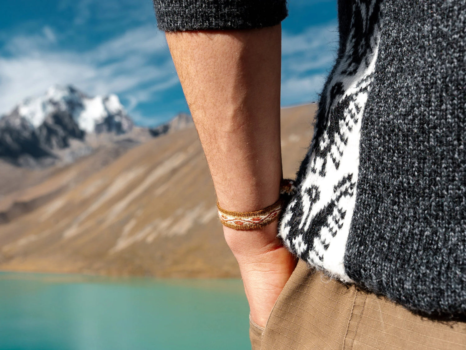 A man wearing an alpaca bracelet looking at a mineral blue lake