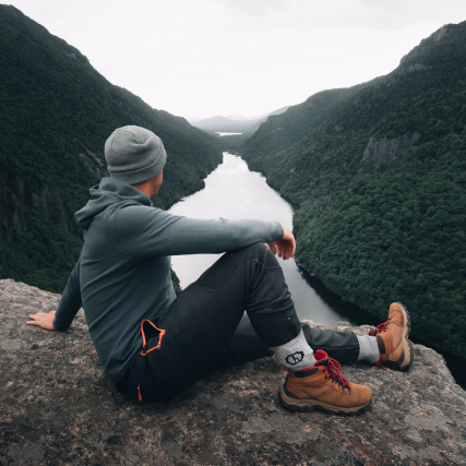 A man looking at a river and the jungle staying cozy in his alpaca crew socks 