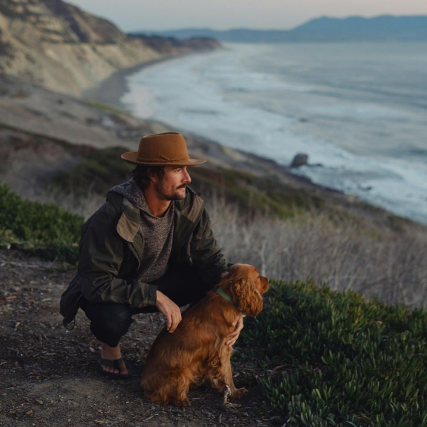 A man and his dog looking at the ocean