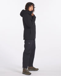 Side view of black Apu Parka with hood and zippered hand pockets, worn in regular fit on white background