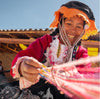 A quechua woman smiling at weaving the alpaca fiber