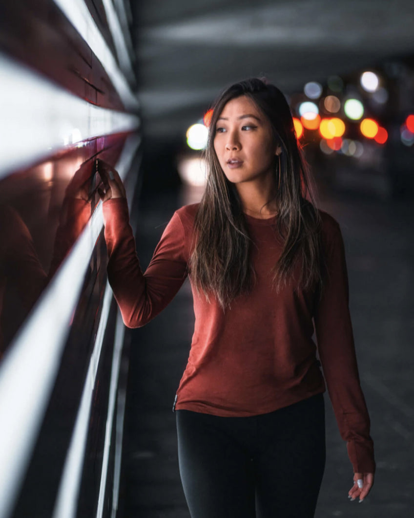 A woman wearing a clay baselayer with car lights in the background
