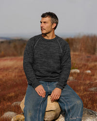 Front view of The Original Crew alpaca crewneck in charcoal showing raglan seams and relaxed fit on model in a field