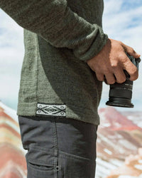 Side close-up of The Original Crew alpaca crewneck in eucalyptus showing knit texture and woven hem tag on a model