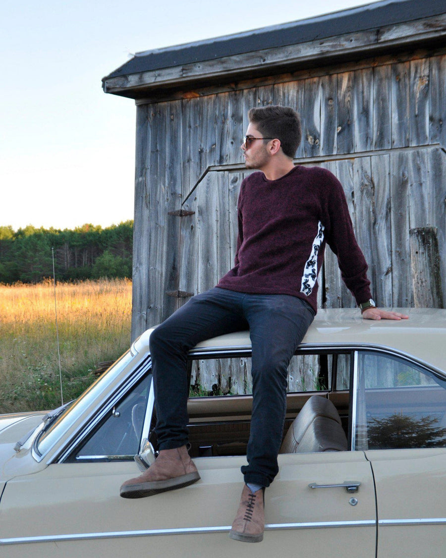 Man sitting on a vintage car in front of a wooden barn