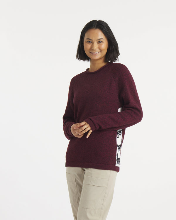 Woman wearing a maroon sweater with a patterned side panel on a white background