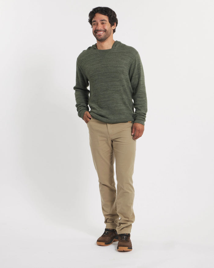 Man wearing a green sweater and beige pants on a white background