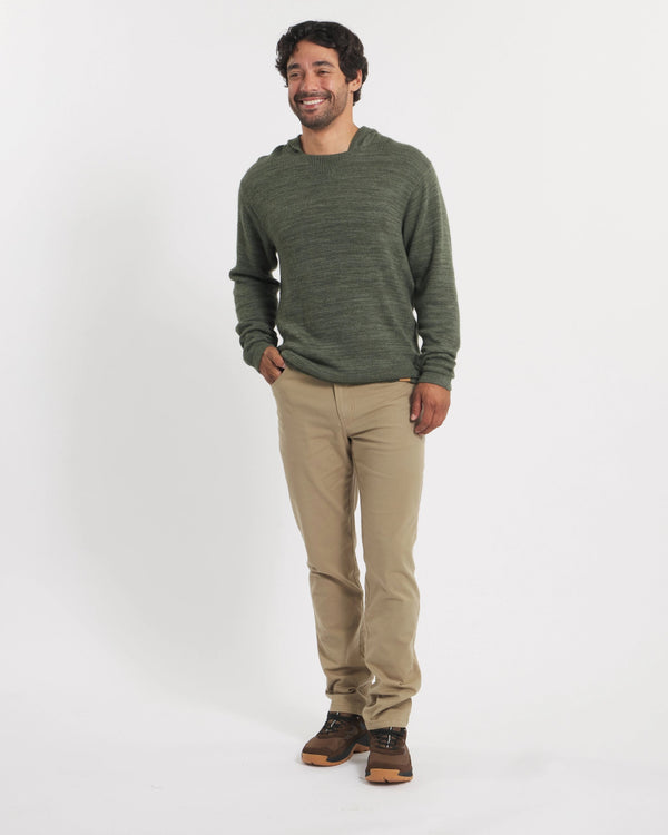 Man wearing a green sweater and beige pants on a white background