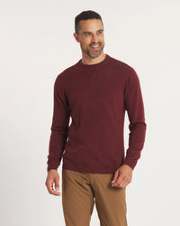 Man wearing a maroon sweater and brown pants on a white background