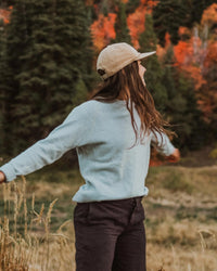 Woman in Sky Blue Crewneck Alpaca Wool Outdoor Sweater in Front of Fall Foliage - PAKA The Original Crew