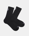 Flat lay of Trail 3/4 Crew Socks, black, with cushioned footbed and white PAKA logo on cuff and toe on light background