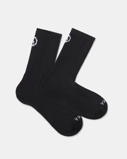 Flat lay of Trail 3/4 Crew Socks, black, with cushioned footbed and white PAKA logo on cuff and toe on light background