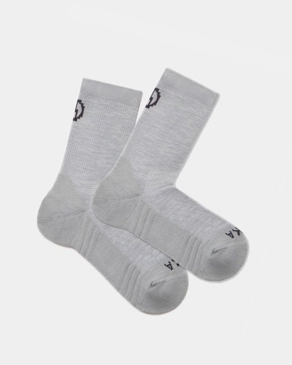 Flat lay of Trail 3/4 crew socks in light gray showcasing cushioned sole and black PAKA logo on cuff and toe on white background