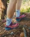 Model wearing light blue Trail 3/4 crew socks hiking on a rocky trail