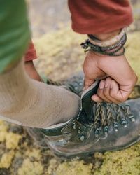Close-up of Trail 1/4 Crew sock on foot showcasing quarter-height fit and cushioned ankle inside a hiking boot on a mossy trail