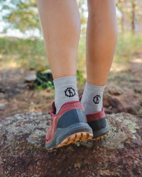 Person wearing Silver socks with a black logo and red shoes on a natural background