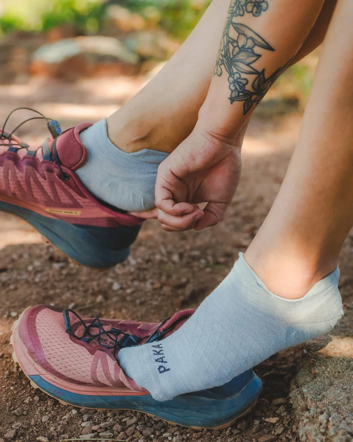 Side view of Trail Ankle Socks (alpaca socks) showcasing low-cut ankle fit and PAKA logo on a dirt trail background