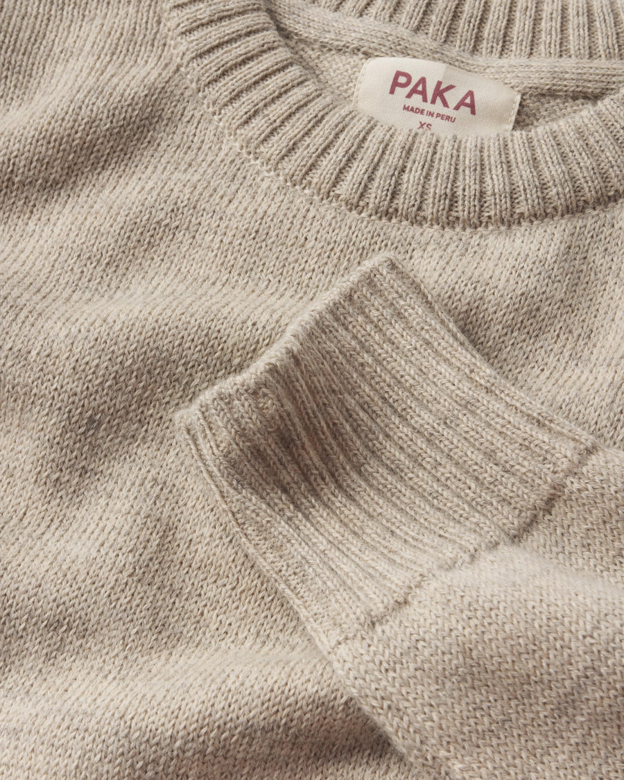 Close-up of a beige sweater with 'PAKA' label on a matching background