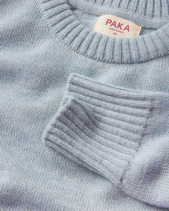 Close-up of a light blue sweater with a PAKA label on a matching background