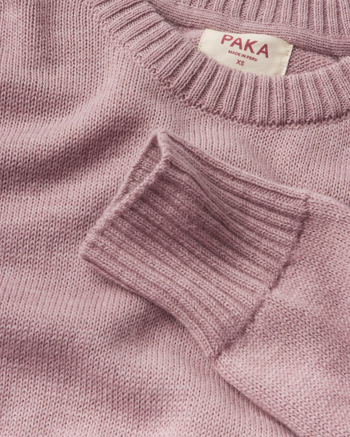 Close-up of a pink sweater with 'Paka' label on a matching background