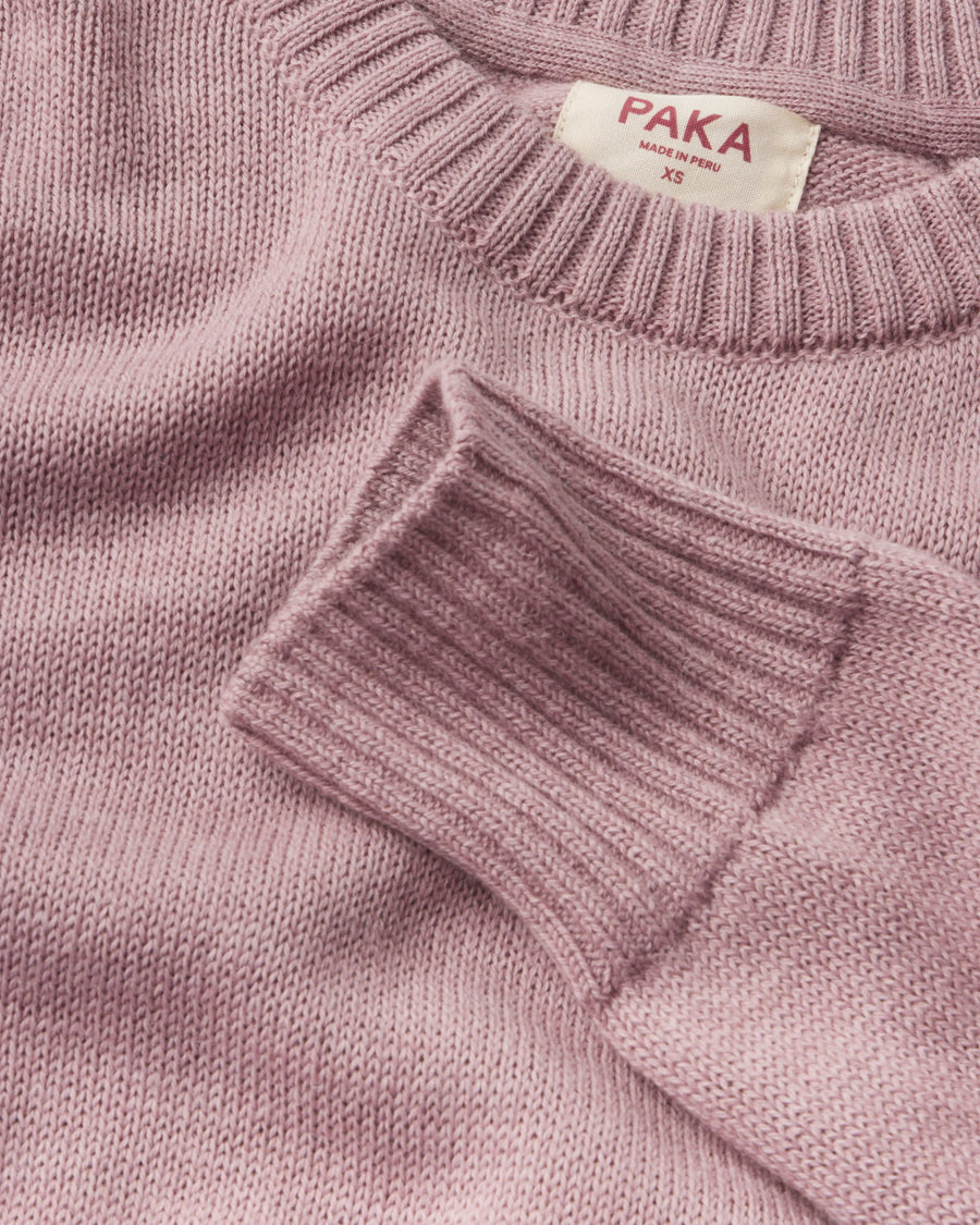 Close-up of a pink sweater with 'Paka' label on a matching background