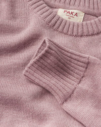 Close-up of a pink sweater with 'Paka' label on a matching background