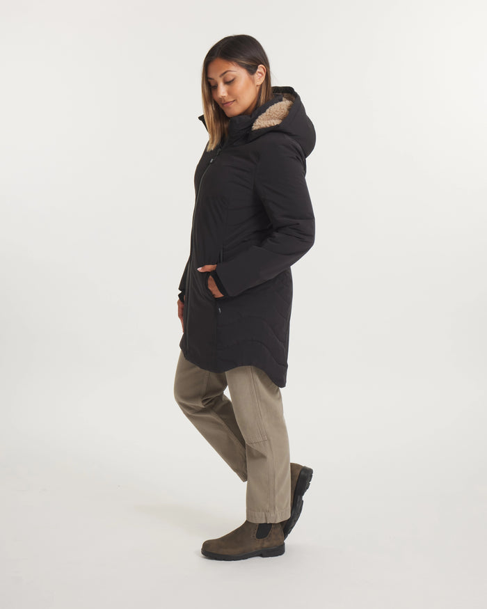 Person wearing a black coat with a fur-lined hood on a white background