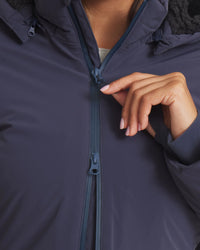 Person zipping up a dark blue jacket